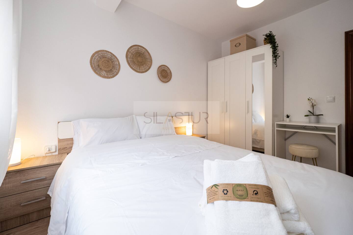 Double bedroom with white bedding and wicker wall decor